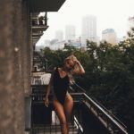 Blondynka w czarnym kostiumie kąpielowym stojąca na balkonie