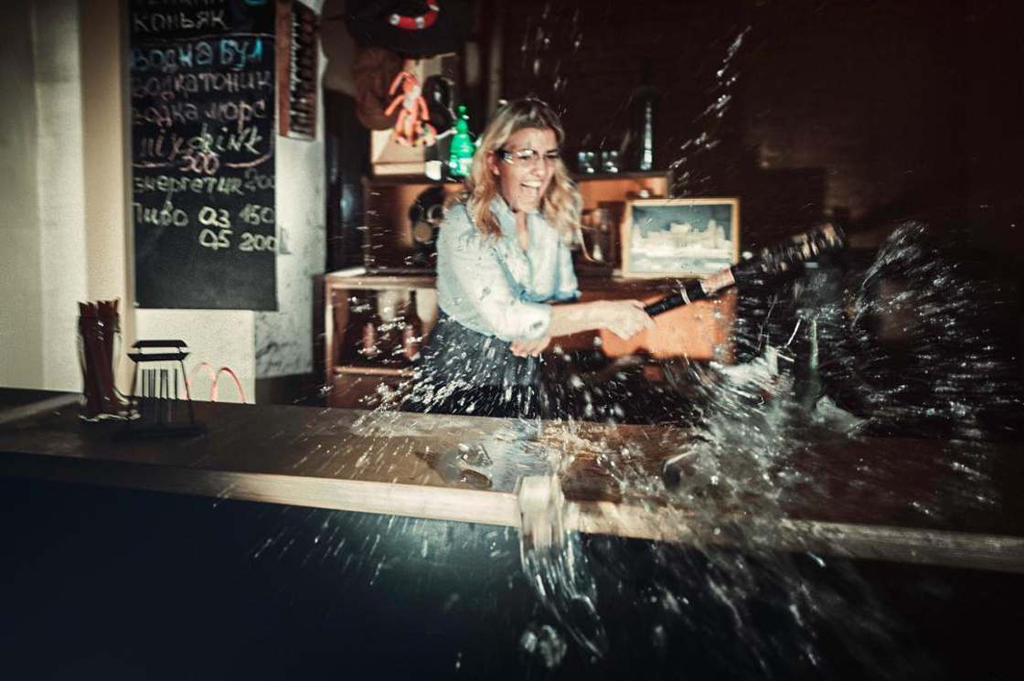 Kobieta rozbija szklane wyposażenie baru
