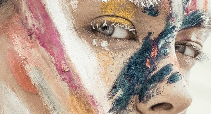 Portret dziewczyny z pomalowaną różnymi kolorami farb twarzą