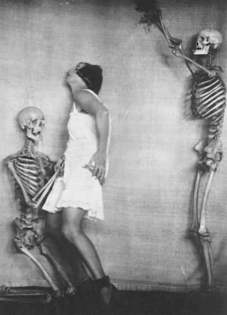 Kobieta stojąca obok szkieletu, za nią drugi szkielet