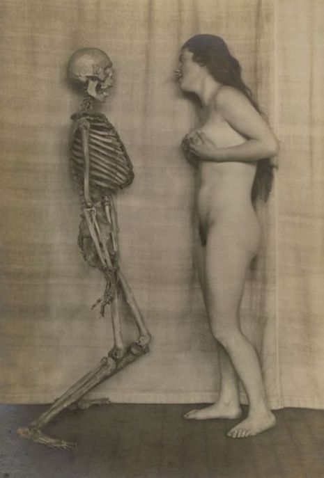 Naga kobieta stojąca naprzeciwko szkieletu