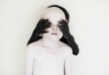 Czarne dziecko zakrywa albinosowi oczy.