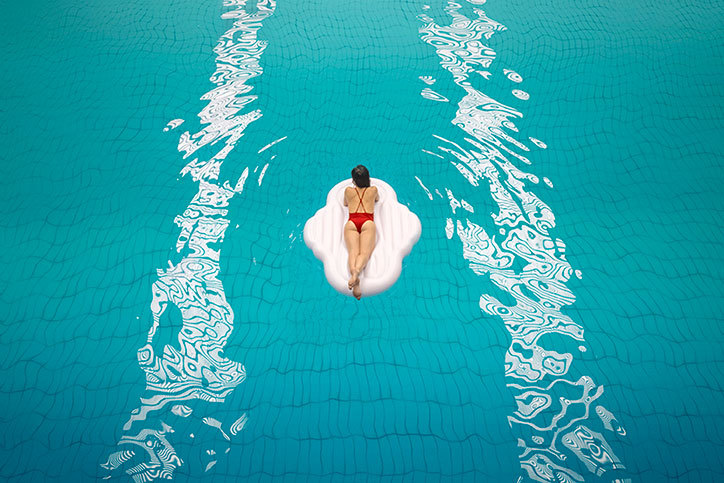 Kobieta pływająca na dmuchanym materacu w basenie.