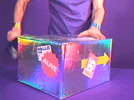 Człowiek obracający pudełkiem zapakowanym w holograficzny papier