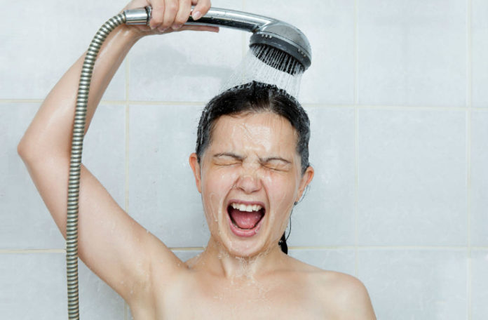 Kobieta oblewająca się wodą ze słuchawki prysznicowej