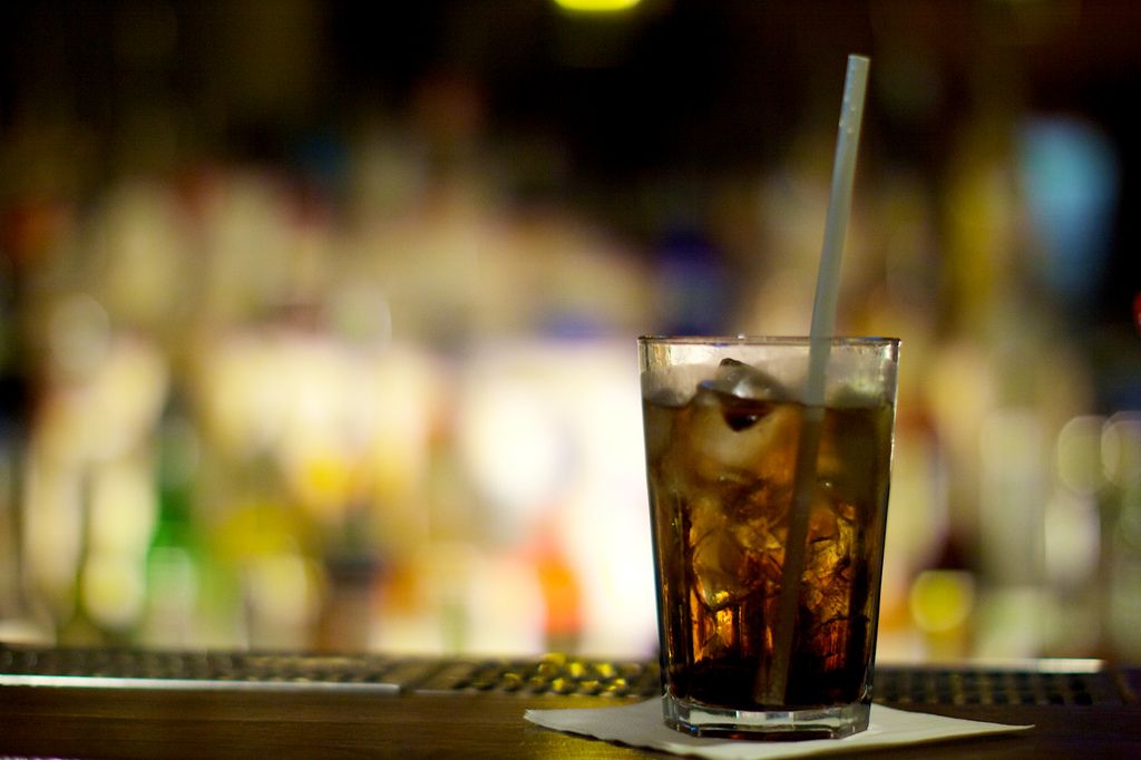 Szklanka rumu z lodem i słomką stojąca na stole