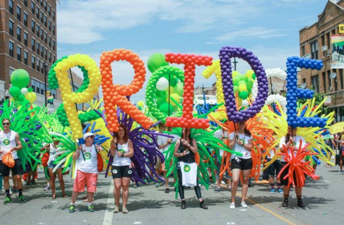 Ludzie stojący z napisem PRIDE zrobionym z balonów