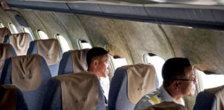 Wnętrze samolotu z brudynymi fotelami i dwójką ludzi