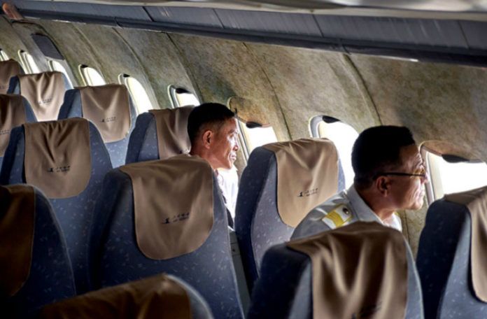 Wnętrze samolotu z brudynymi fotelami i dwójką ludzi