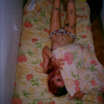 Dziewczyna leżąca na łóżku w samych majtkach, zakrywająca się poduszką