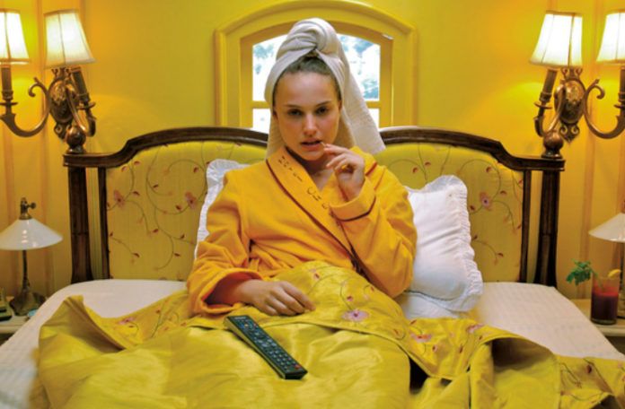 Kobieta leżąca w żółtym łóżku w żółtym pokoju, z ręcznikiem na głowie