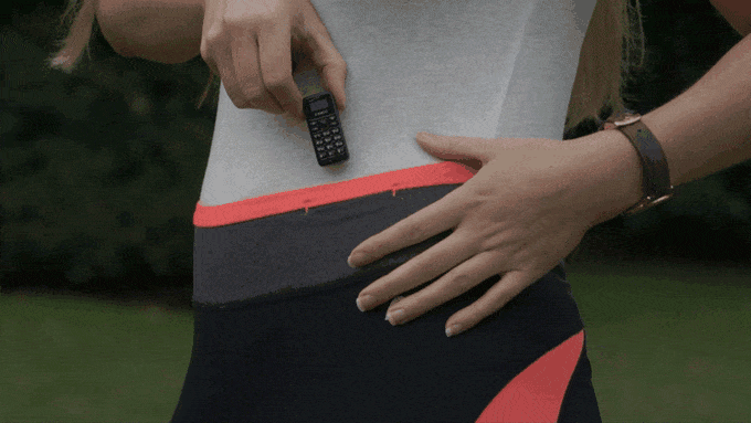 Dziewczyna wkładająca telefon za pasek od spodni do biegania