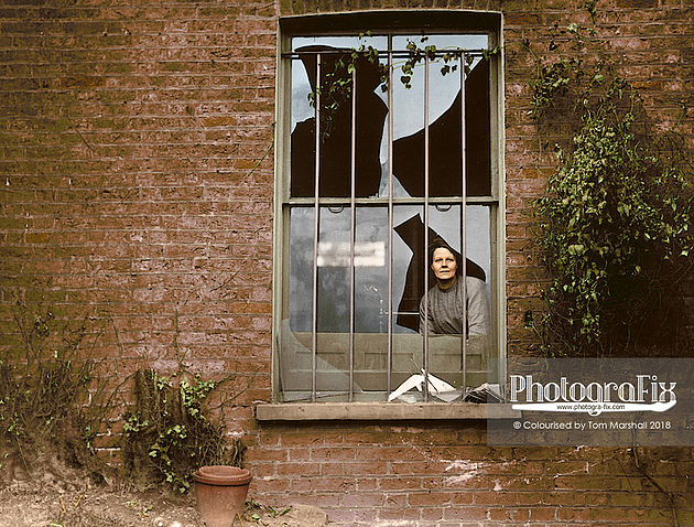 Kobieta stojąca za potłuczoną szybą okna