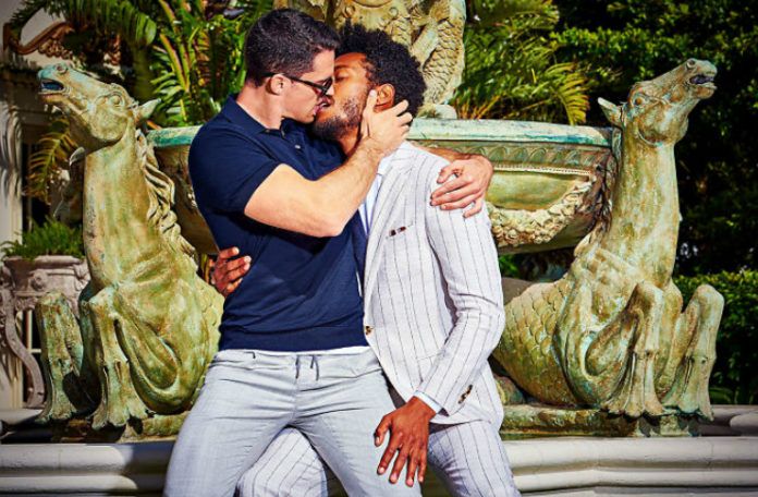 Dwóch mężczyzn w garniturach całujących się przy fontannie