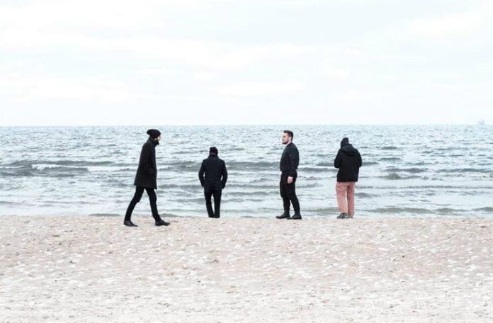 Czterech mężczyzn stojących nad brzegiem morza
