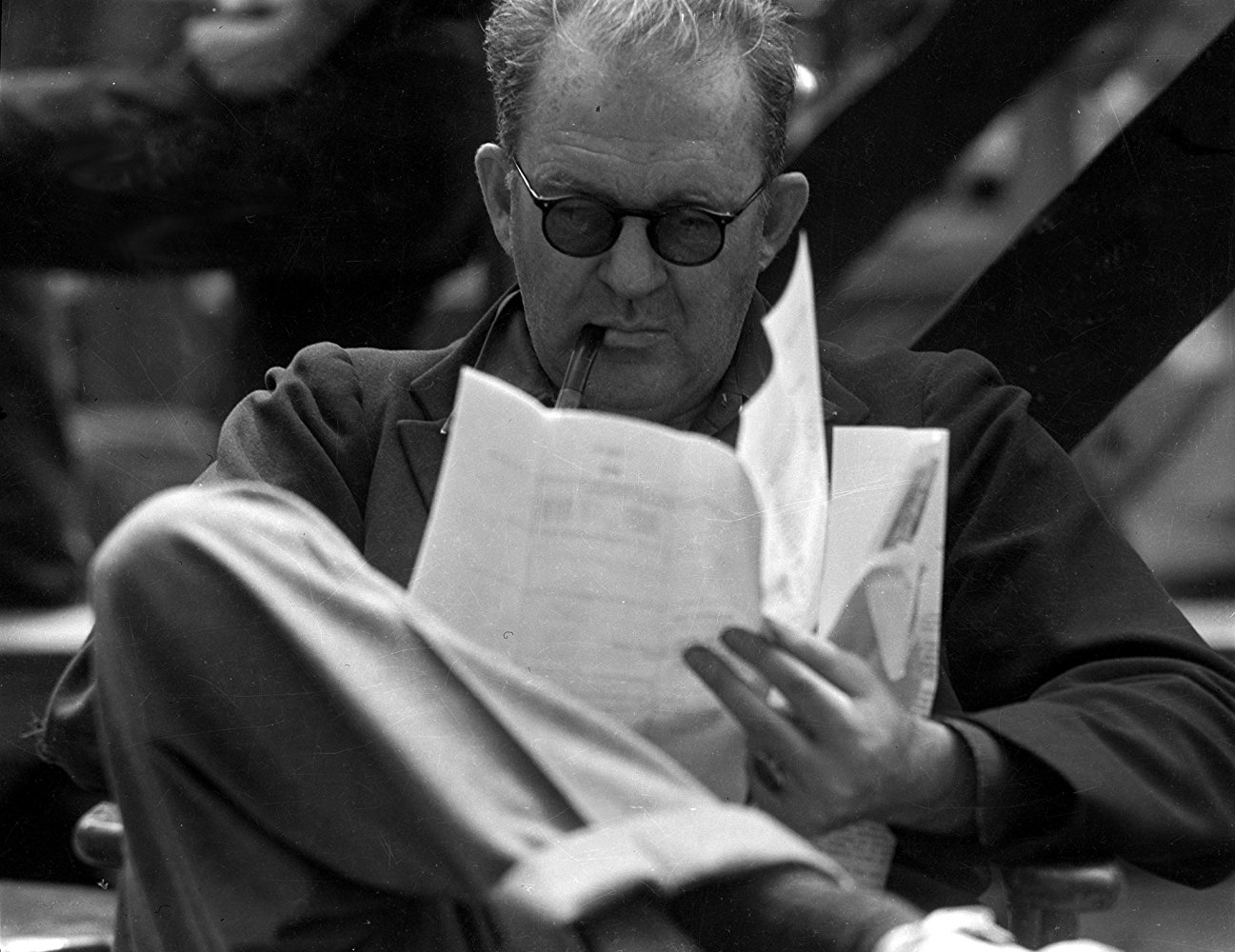 Reżyser John Ford siedzący z fajką i czytający scenariusz