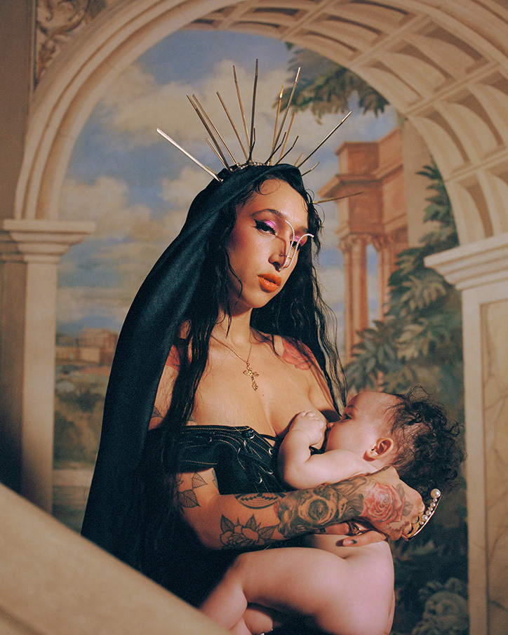 Kobieta w czarnej sukience z dzieckiem przy piersi