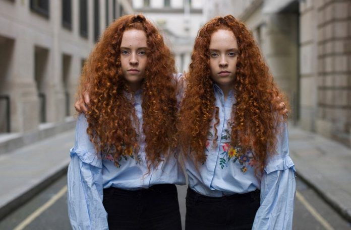 Dwie rudowłose bliźniaczki jednojajowe ubrane w takie same ubrania