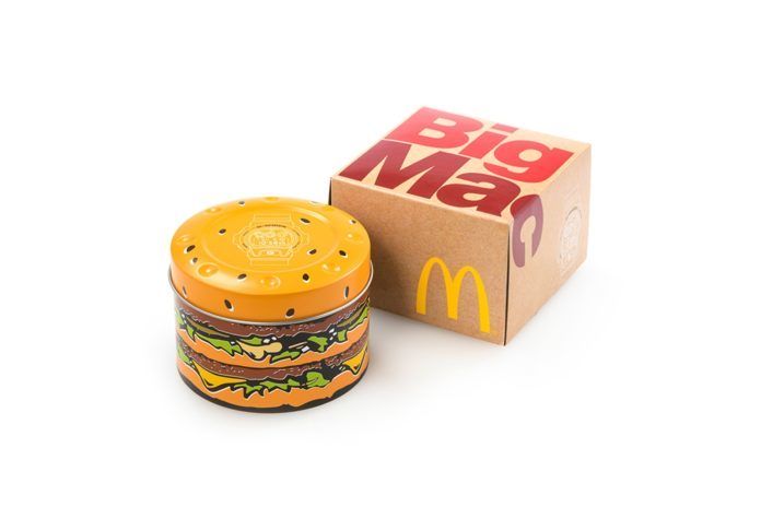 Papierowe pudełko z napisem Big Mac i puszka w kształcie hamburgera na białym tle.