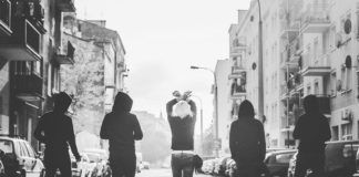 Czarno-biale zdjęcie przedstawiające cztery osoby idące tyłem do ulicy