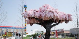 Kwitnące drzewo wiśniowe zrobione z klocków Lego na tle placu zabaw.
