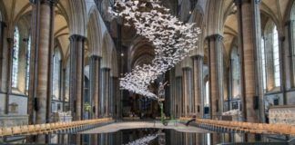 Wnętrze gotyckiej katedry wypełnione mnóstwem białych papierowych ptaków.