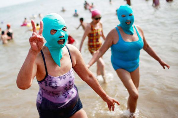Ludzie w maskach zakrywających twarz siedzący na plazy