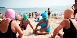 Ludzie w maskach zakrywających twarz siedzący na plazy