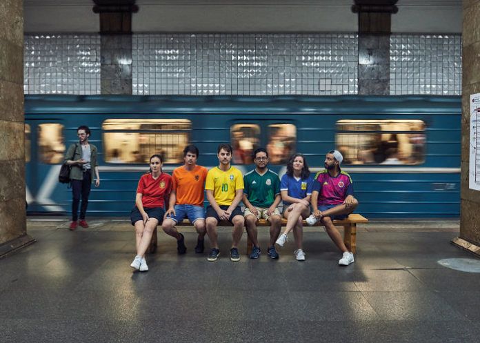 Grupa ludzi ubrana w kolorowe koszulki układające się w tęcze