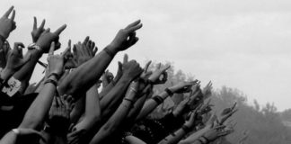 Czarno-białe zdjęcie wyciągniętych rąk podczas koncertu