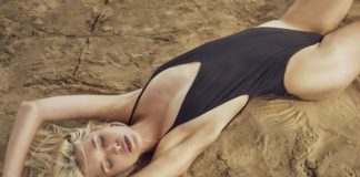 Dziewczyna w czarnym kostiumie leżąca na piasku