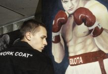 Chłopak w czarnej bluzie na tle plakatu z bokserem