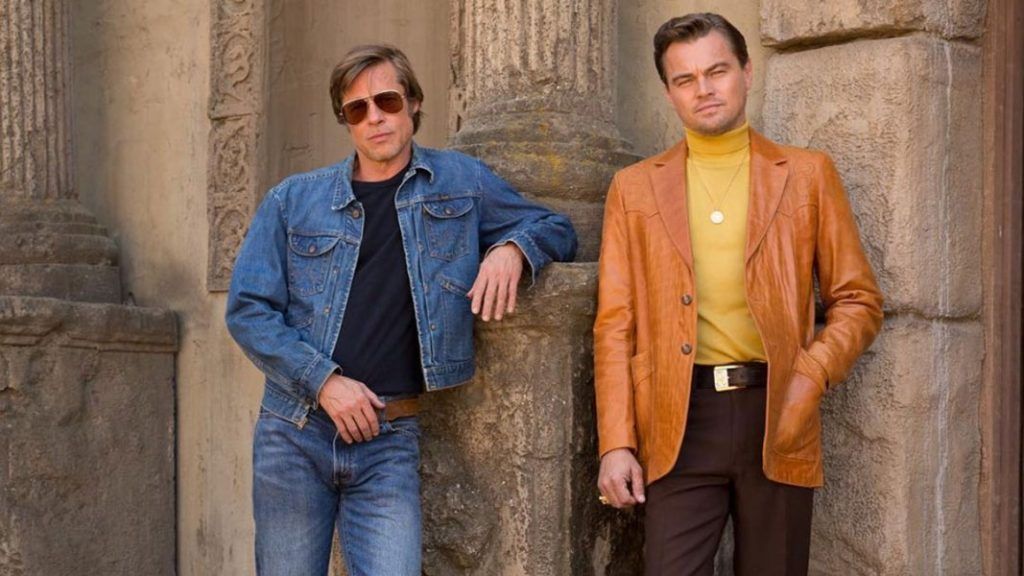 po lewej Brad pitt ubrany w jeansową kurtkę i okulary przeciw słoneczne, po prawej Leonardo Di Caprio w skórzanej kurtce i żółtym golfie