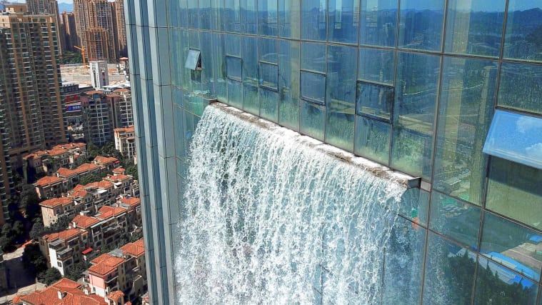 Sztuczny wodospad wypływający z wieżowca w Chinach, widok na spływającą w dół wodę znad miejsca wypływania