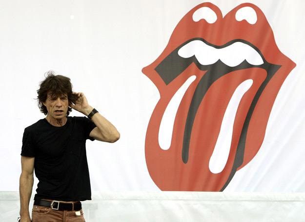mężczyzna (Mick Jagger) na tle symbolu zespołu the rolling stones ust z wyciągniętym językiem