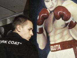 Chłopak w czarnej bluzie na tle plakatu z bokserem