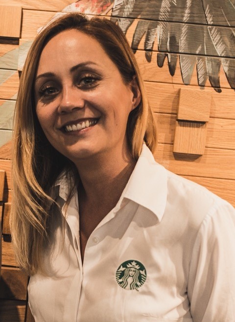 Uśmiechnięta kobieta w białej koszuli z logo Starbucsk