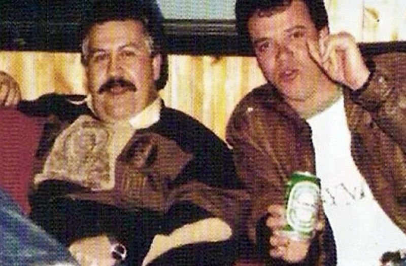 Mężczyzna z wąsem i mężczyzna trzymający puszkę z piwem siedzą na kanapie