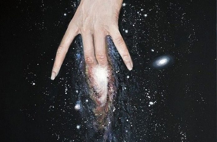 Dłoń kobiety na tle galaktyki
