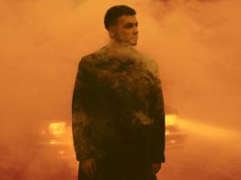 Mężczyzna w płaszczu na tle pomarańczowej mgły