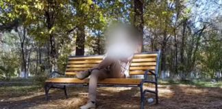 Mężczyzna siedzący na ławce z zakrytą twarzą