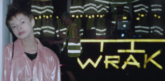 Dziewczyna w różowej kurtce i krótkich włosach na tle napisu WRAK
