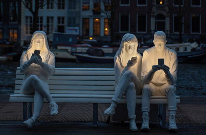Rzeźba przedstawiająca trójkę ludzi ze smartfonami