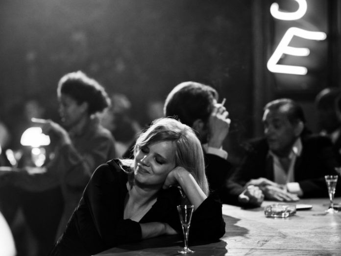 Czarno-białe zdjęcie dziewczyny siedzącej przy barze
