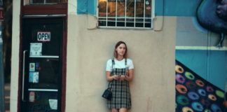 Dziewczyna w sukience w kartę stojąca pod ścianą