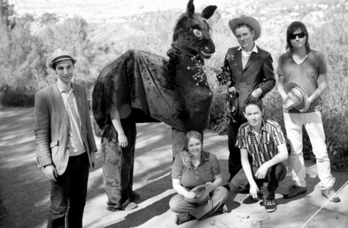 Czarno-białe zdjęcie grupy ludzi stojących z koniem