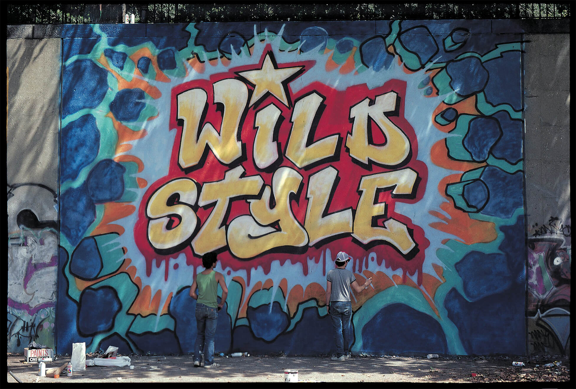 Na zdjeciu widzimy sciane pokryta kolorowym grafitti najbardziej rzuca sie w oczy napis wild style
