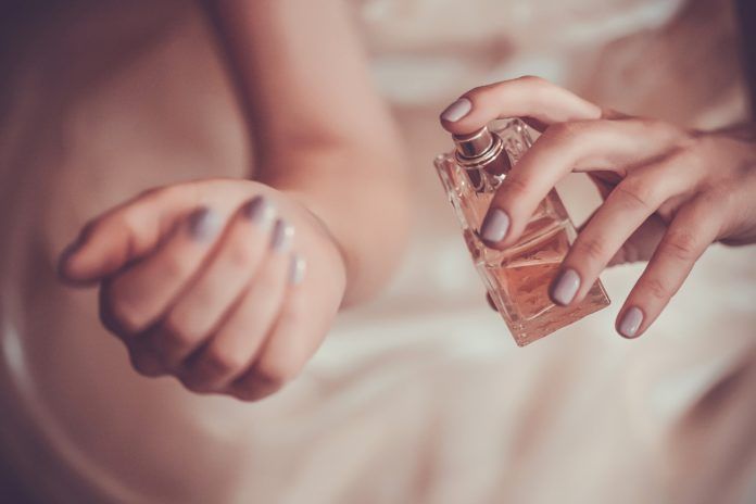 Kobieca dłoń pryskająca nagdarstek perfumami