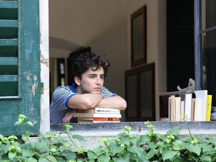 Chłopak wyglądający przez okno, oparty o książki
