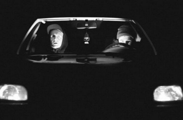 Dwóch mężczyzn w czapkach w czarnym samochodzie